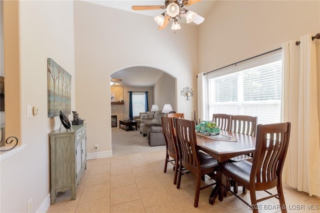 4331 Sunset Dr Unit B, Osage Beach, MO 65065 - dining area with arched walkways, a towering ceiling, a ceiling fan, a fireplace, and light tile patterned floors