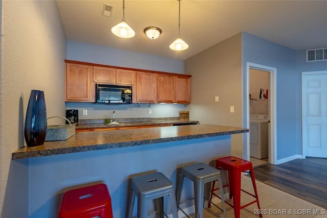 275 Flynn Rd Unit 105, Lake Ozark, MO 65049 - kitchen with black microwave, a peninsula, dark countertops, a breakfast bar, and decorative light fixtures