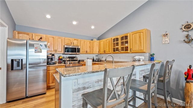 15 Knox Point Cir, Lake Ozark, MO 65049 - kitchen with appliances with stainless steel finishes, light stone counters, glass insert cabinets, backsplash, and lofted ceiling
