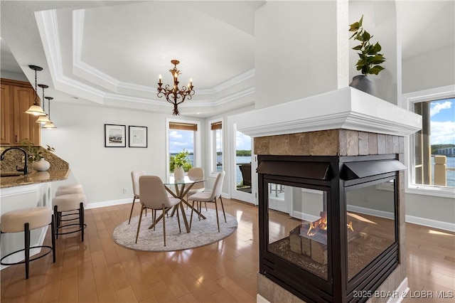 1129 Beacon Pointe Cir, Lake Ozark, MO 65049 - dining space with a tray ceiling, healthy amount of natural light, a multi sided fireplace, a chandelier, and crown molding