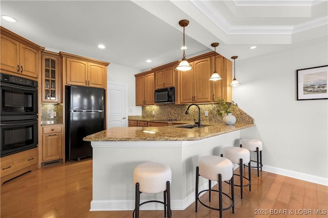 1129 Beacon Pointe Cir, Lake Ozark, MO 65049 - kitchen featuring black appliances, light wood-style floors, a breakfast bar, light stone countertops, and a peninsula