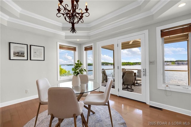 1129 Beacon Pointe Cir, Lake Ozark, MO 65049 - dining room featuring a raised ceiling, crown molding, a chandelier, hardwood / wood-style floors, and a water view