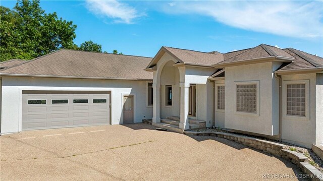 1129 Beacon Pointe Cir, Lake Ozark, MO 65049 - ranch-style house featuring driveway, an attached garage, and stucco siding