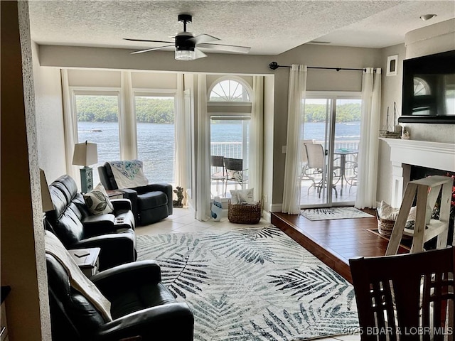 757 Malibu Rd Unit 101B, Osage Beach, MO 65065 - living room with a ceiling fan, a water view, a textured ceiling, and a fireplace