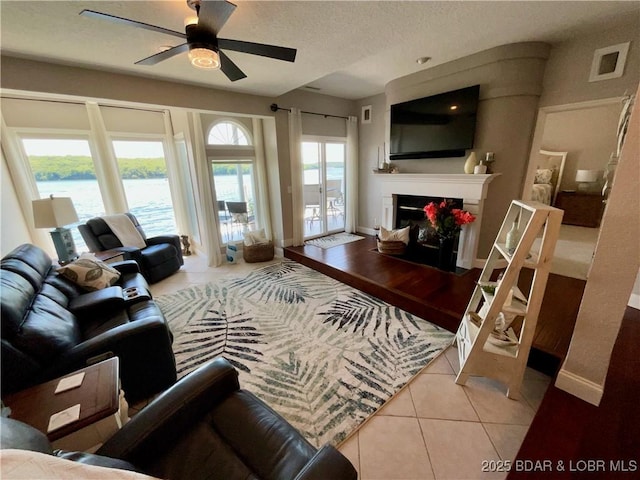 757 Malibu Rd Unit 101B, Osage Beach, MO 65065 - tiled living area featuring ceiling fan, a fireplace, a water view, and a textured ceiling