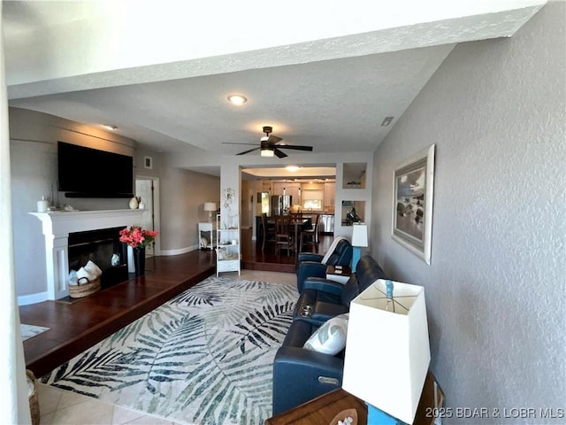 757 Malibu Rd Unit 101B, Osage Beach, MO 65065 - living room with a textured wall, a ceiling fan, and a glass covered fireplace