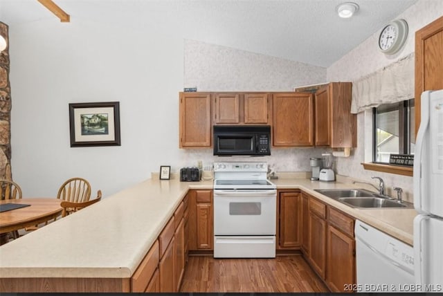 611 Lazy Days Rd Unit B11, Osage Beach, MO 65065 - kitchen with white appliances, vaulted ceiling, a peninsula, light countertops, and wood finished floors