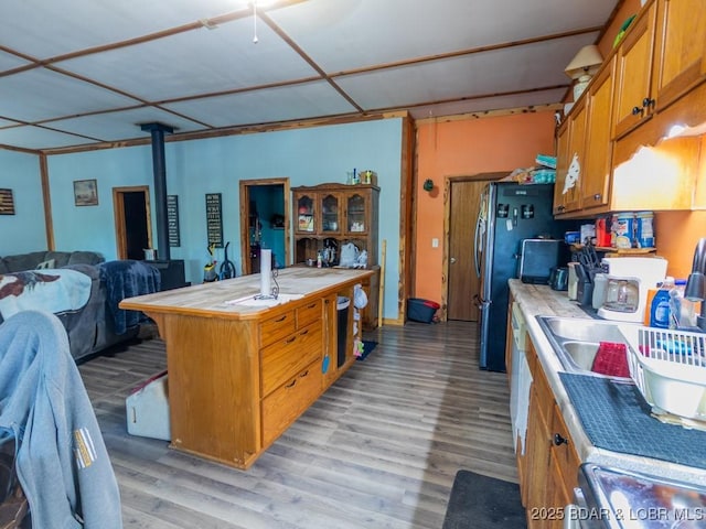 1727 Bollinger Creek Rd, Climax Springs, MO 65324 - kitchen featuring brown cabinetry, tile countertops, light wood-type flooring, open floor plan, and a kitchen breakfast bar