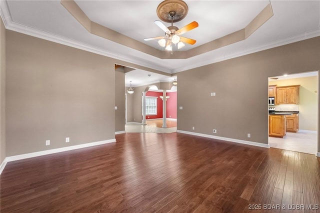 22 Hand Ln, Eldon, MO 65026 - unfurnished living room featuring ceiling fan, a tray ceiling, decorative columns, dark wood-type flooring, and ornamental molding