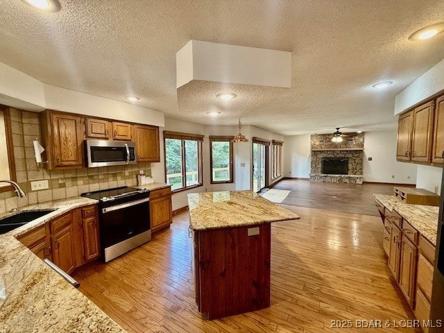 170 Twin Oaks Dr, Lake Ozark, MO 65049 - kitchen featuring stainless steel appliances, a textured ceiling, open floor plan, brown cabinetry, and a kitchen island