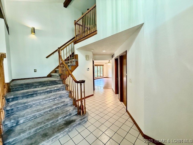 170 Twin Oaks Dr, Lake Ozark, MO 65049 - staircase with tile patterned floors, beam ceiling, and high vaulted ceiling