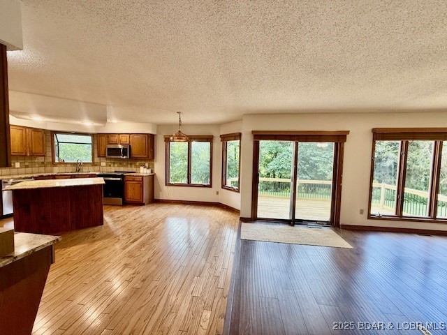 170 Twin Oaks Dr, Lake Ozark, MO 65049 - kitchen with a textured ceiling, stainless steel appliances, open floor plan, light countertops, and brown cabinets