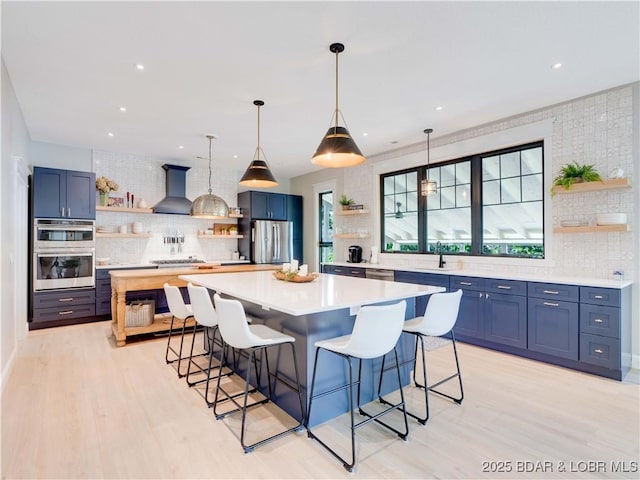 92 Arrowhead Beach Rd, Lake Ozark, MO 65049 - kitchen with open shelves, wall chimney range hood, light countertops, stainless steel appliances, and recessed lighting