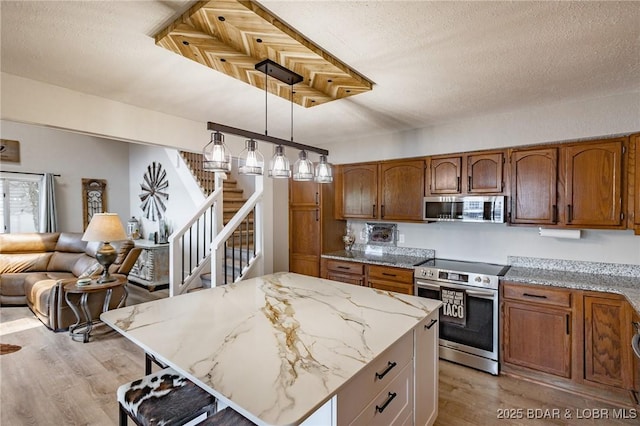 35 Port Bagnell W, Eldon, MO 65026 - kitchen featuring stainless steel appliances, light wood finished floors, brown cabinets, light stone countertops, and pendant lighting