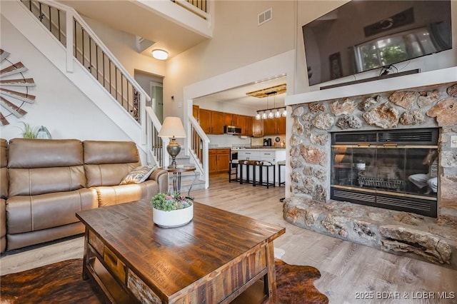 35 Port Bagnell W, Eldon, MO 65026 - living area with a stone fireplace, light wood finished floors, a high ceiling, and stairs