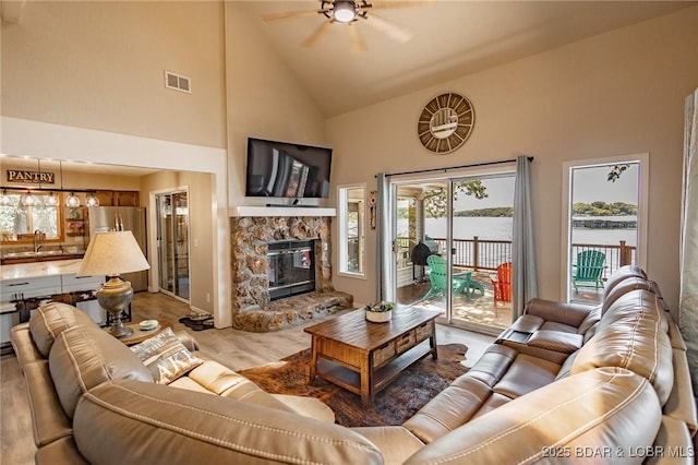 35 Port Bagnell W, Eldon, MO 65026 - living area featuring high vaulted ceiling, ceiling fan, healthy amount of natural light, a fireplace, and light wood-style flooring