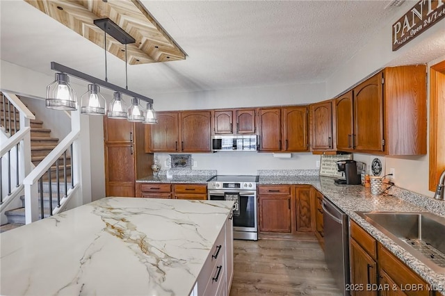 35 Port Bagnell W, Eldon, MO 65026 - kitchen with stainless steel appliances, brown cabinets, wood finished floors, decorative light fixtures, and light stone countertops