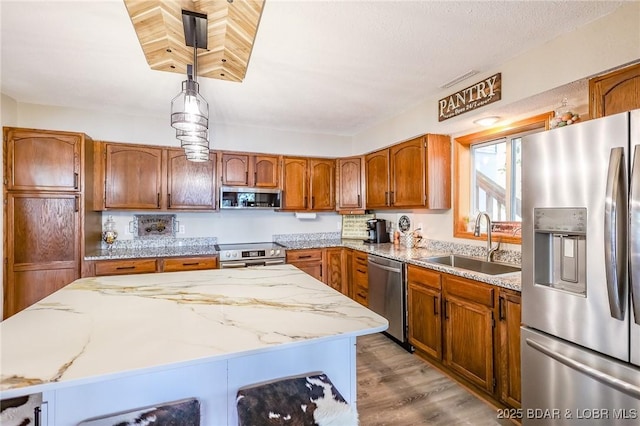 35 Port Bagnell W, Eldon, MO 65026 - kitchen with appliances with stainless steel finishes, brown cabinets, wood finished floors, light stone countertops, and a kitchen island