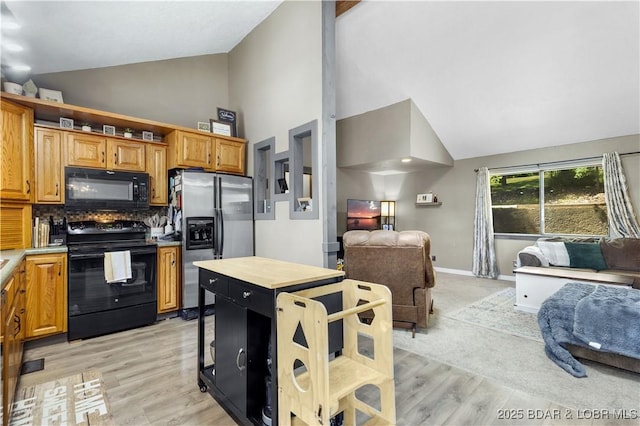 4741 Clearwood Ln, Osage Beach, MO 65065 - kitchen featuring black appliances, open floor plan, high vaulted ceiling, light countertops, and light wood finished floors
