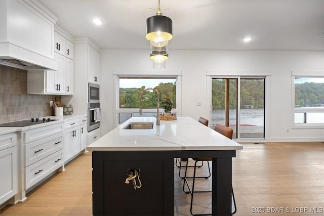 30586 Rapids Holw, Stover, MO 65037 - kitchen with stainless steel appliances, premium range hood, a breakfast bar, backsplash, and light wood-style flooring