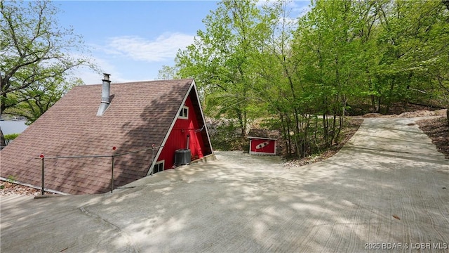 27086 Comanche Cv, Rocky Mount, MO 65072 - view of home's exterior with roof with shingles, a barn, a chimney, and driveway