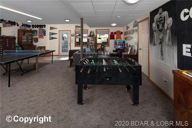 recreation room featuring a drop ceiling and dark colored carpet