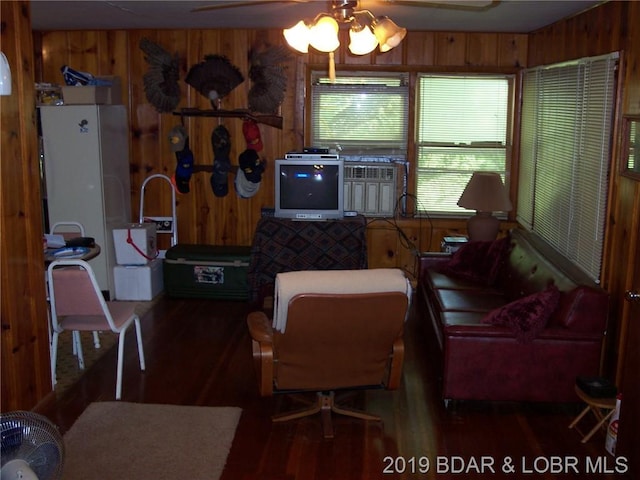 living room featuring ceiling fan, wooden walls, and dark hardwood / wood-style floors