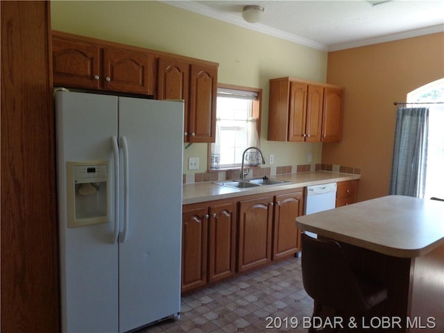 kitchen with crown molding, white appliances, dark tile floors, and sink