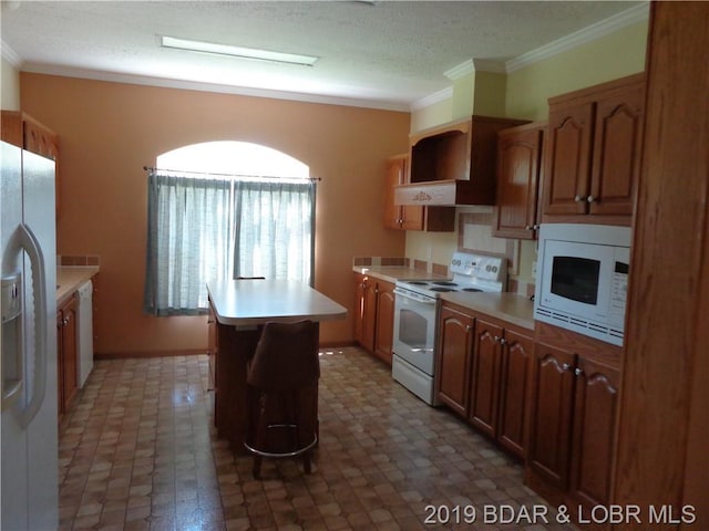 kitchen featuring dark tile flooring, crown molding, and white appliances