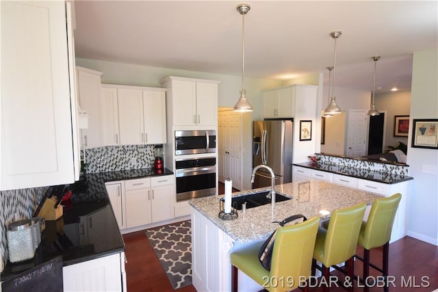 kitchen with dark stone counters, decorative light fixtures, tasteful backsplash, and stainless steel appliances