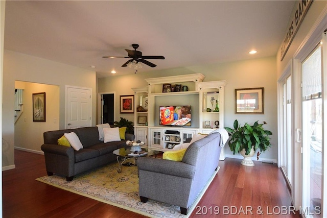 living room with ceiling fan and dark hardwood / wood-style flooring