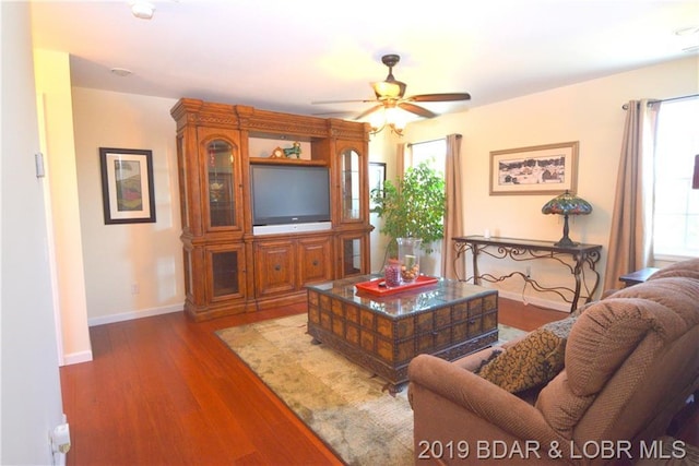 living room featuring ceiling fan, wood-type flooring, and a wealth of natural light