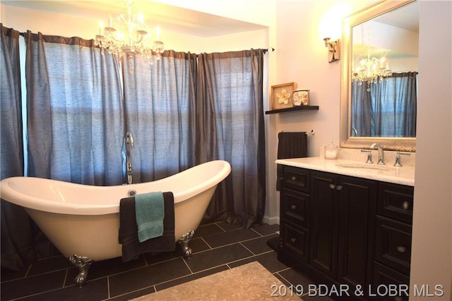 bathroom featuring an inviting chandelier, vanity, tile floors, and a bath to relax in