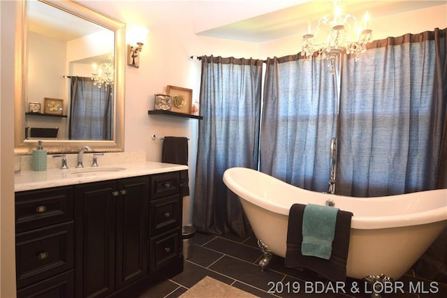 bathroom featuring an inviting chandelier, vanity, tile floors, and a bathtub