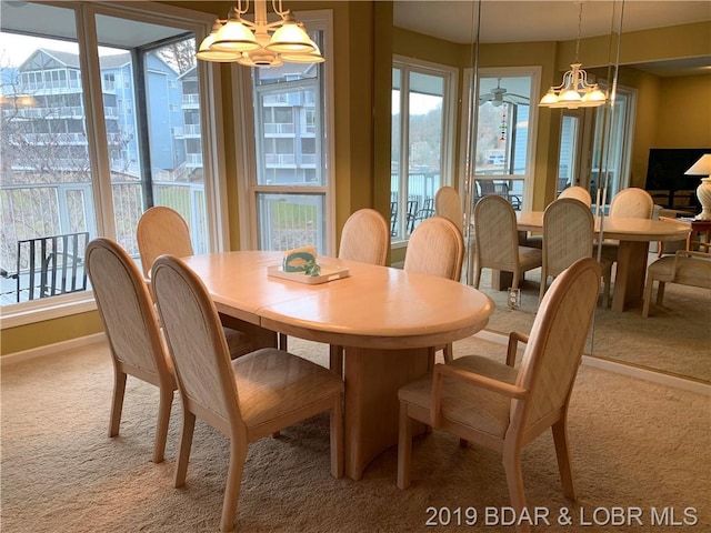 dining room featuring light colored carpet and ceiling fan with notable chandelier