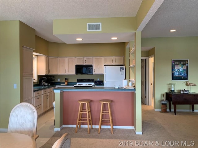 kitchen with a kitchen bar, a textured ceiling, white appliances, and light colored carpet