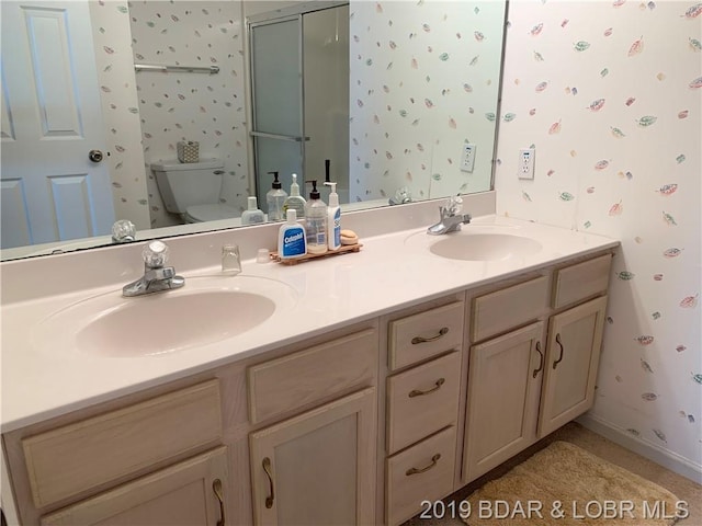 bathroom with double vanity and toilet