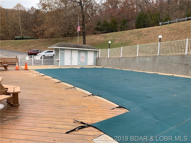 view of swimming pool with a wooden deck and an outdoor structure