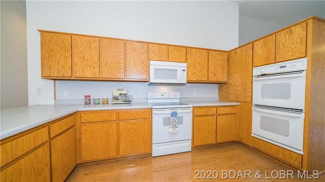 kitchen with a high ceiling, light hardwood / wood-style floors, and white appliances