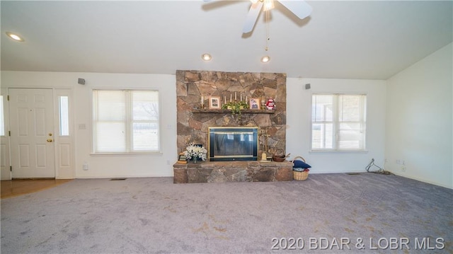 unfurnished living room featuring carpet floors, a stone fireplace, and ceiling fan