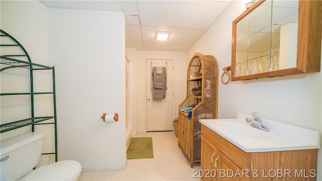 bathroom with a drop ceiling, toilet, and vanity