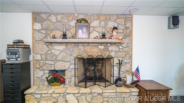 room details with a drop ceiling and a stone fireplace