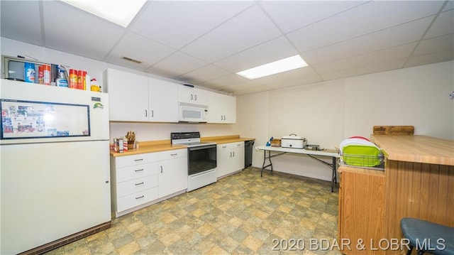 kitchen featuring white appliances, white cabinets, a drop ceiling, and light tile floors