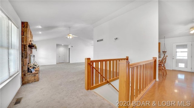 hallway featuring light carpet, plenty of natural light, and vaulted ceiling