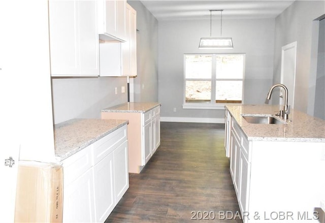 kitchen featuring dark hardwood / wood-style floors, a kitchen island with sink, sink, light stone counters, and white cabinets