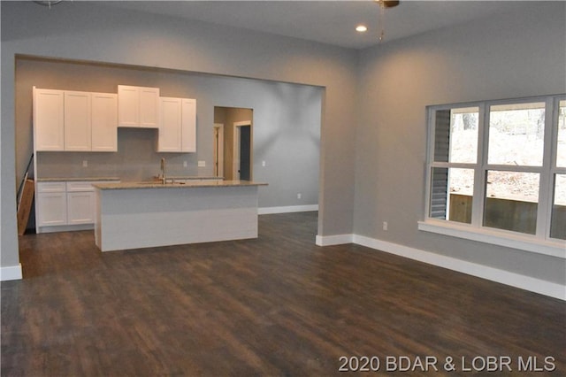 kitchen featuring white cabinets, backsplash, dark hardwood / wood-style flooring, and a center island with sink