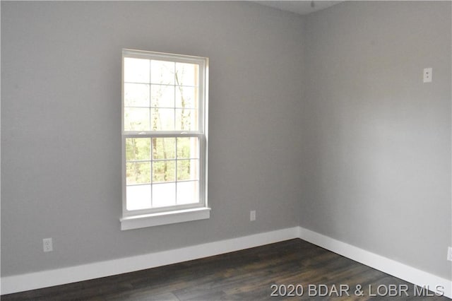 empty room with dark hardwood / wood-style floors and a healthy amount of sunlight