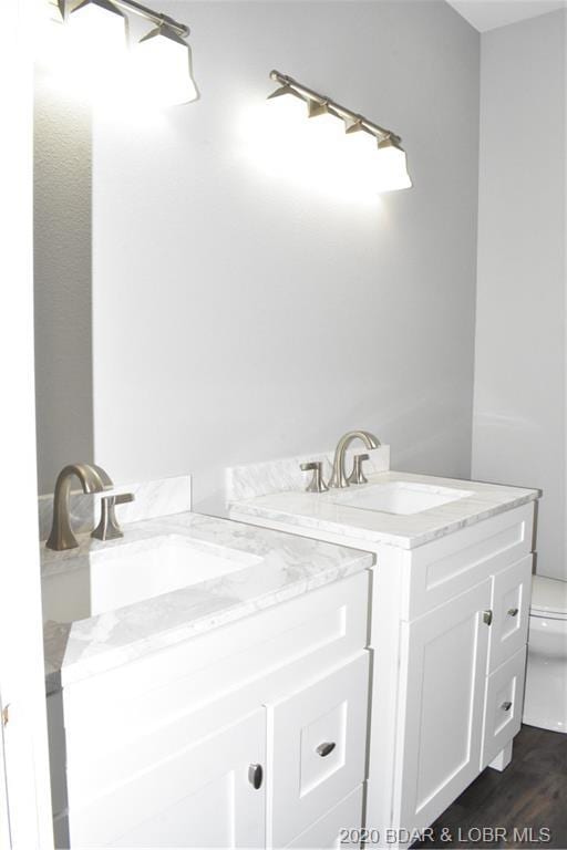 bathroom featuring toilet, vanity, and hardwood / wood-style floors