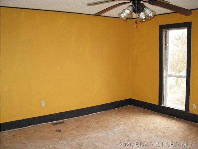 unfurnished room with ceiling fan, a textured ceiling, and a healthy amount of sunlight