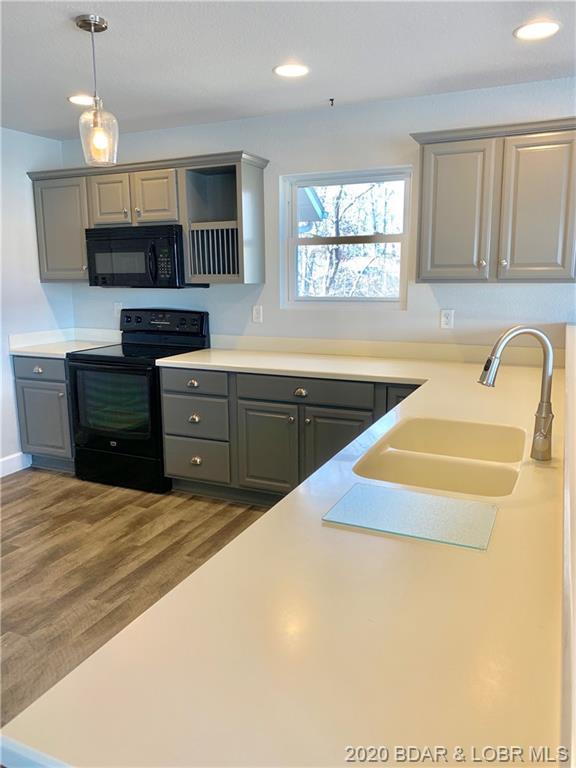 kitchen featuring dark wood-type flooring, sink, gray cabinets, and black appliances